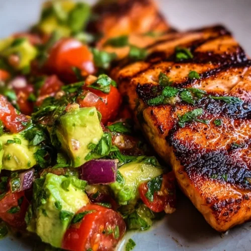 Grilled Salmon with Avocado Salsa 2 Grilled salmon fillet topped with refreshing avocado salsa on a plate.