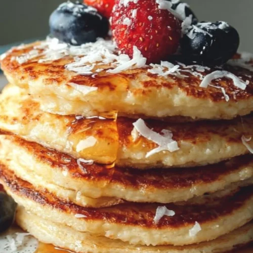 Keto Coconut Flour Pancakes 2 Delicious Keto Coconut Flour Pancakes stacked on a plate with syrup and berries