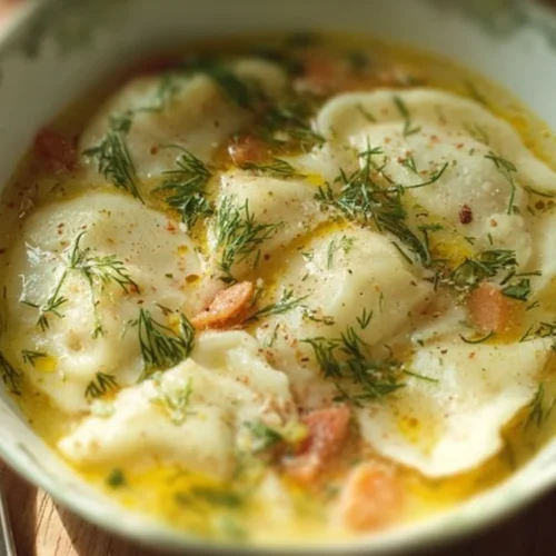 A bowl of creamy Pierogi Dill Soup garnished with fresh dill and potatoes.