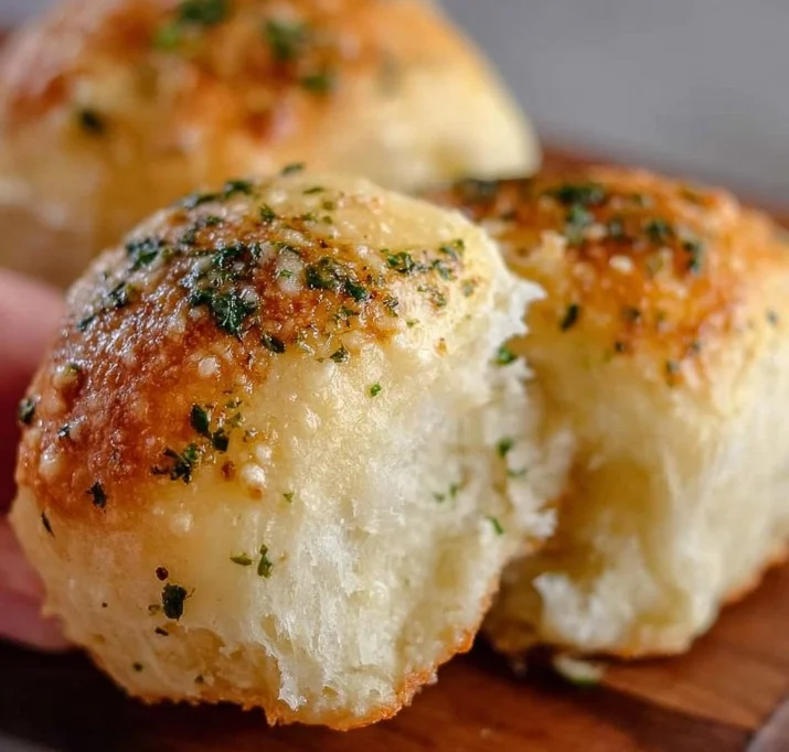 30-Minute Garlic Parmesan Dinner Rolls 1 Freshly baked garlic parmesan dinner rolls on a wooden table