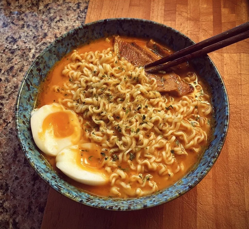 This ramen soup is truly delicious!! 1 A bowl of delicious ramen soup garnished with dumplings and green onions.