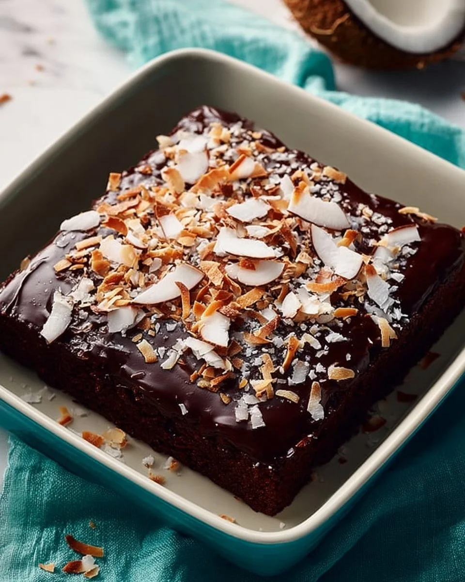 Slice of delicious chocolate coconut cake topped with coconut flakes.