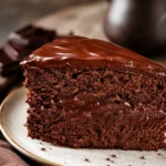 Delicious vegan chocolate cake topped with chocolate frosting and fresh berries.